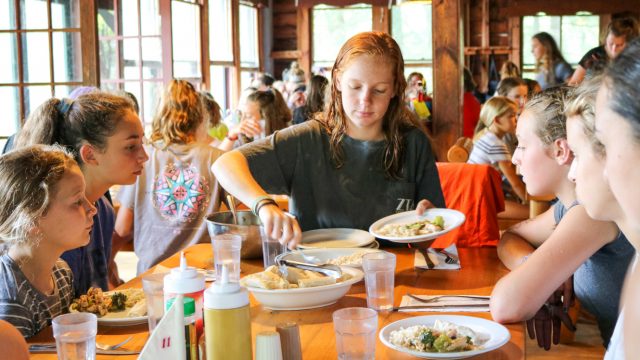 Camper serves food to others at table