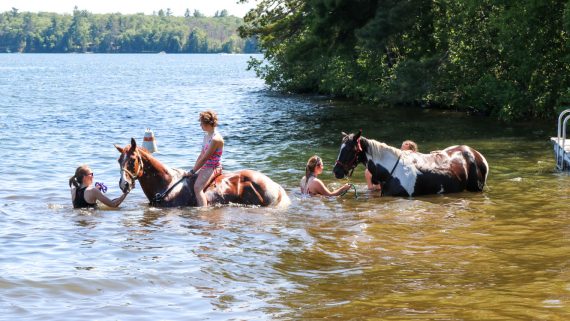 Campers ride horses into the water