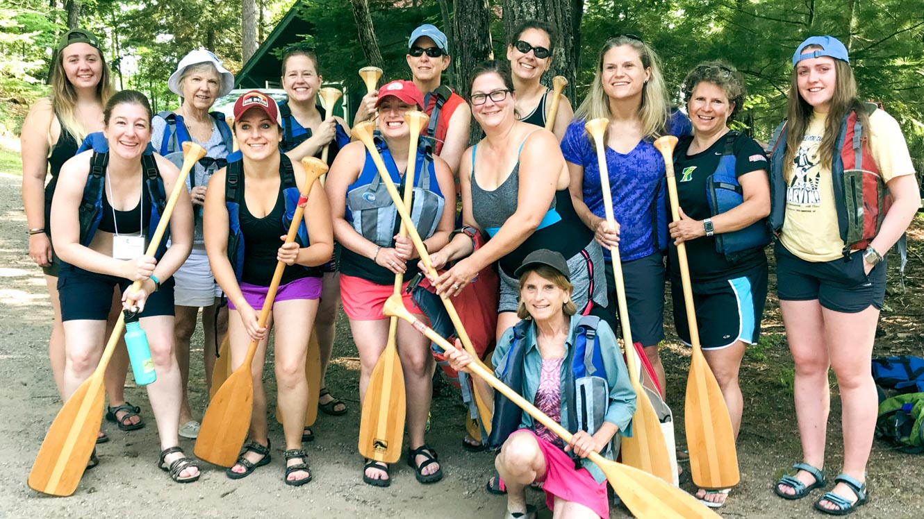 85th Alumni Reunion group holding canoe paddles