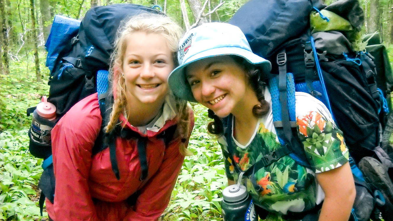Girls smile at the camera on camp backpacking trip