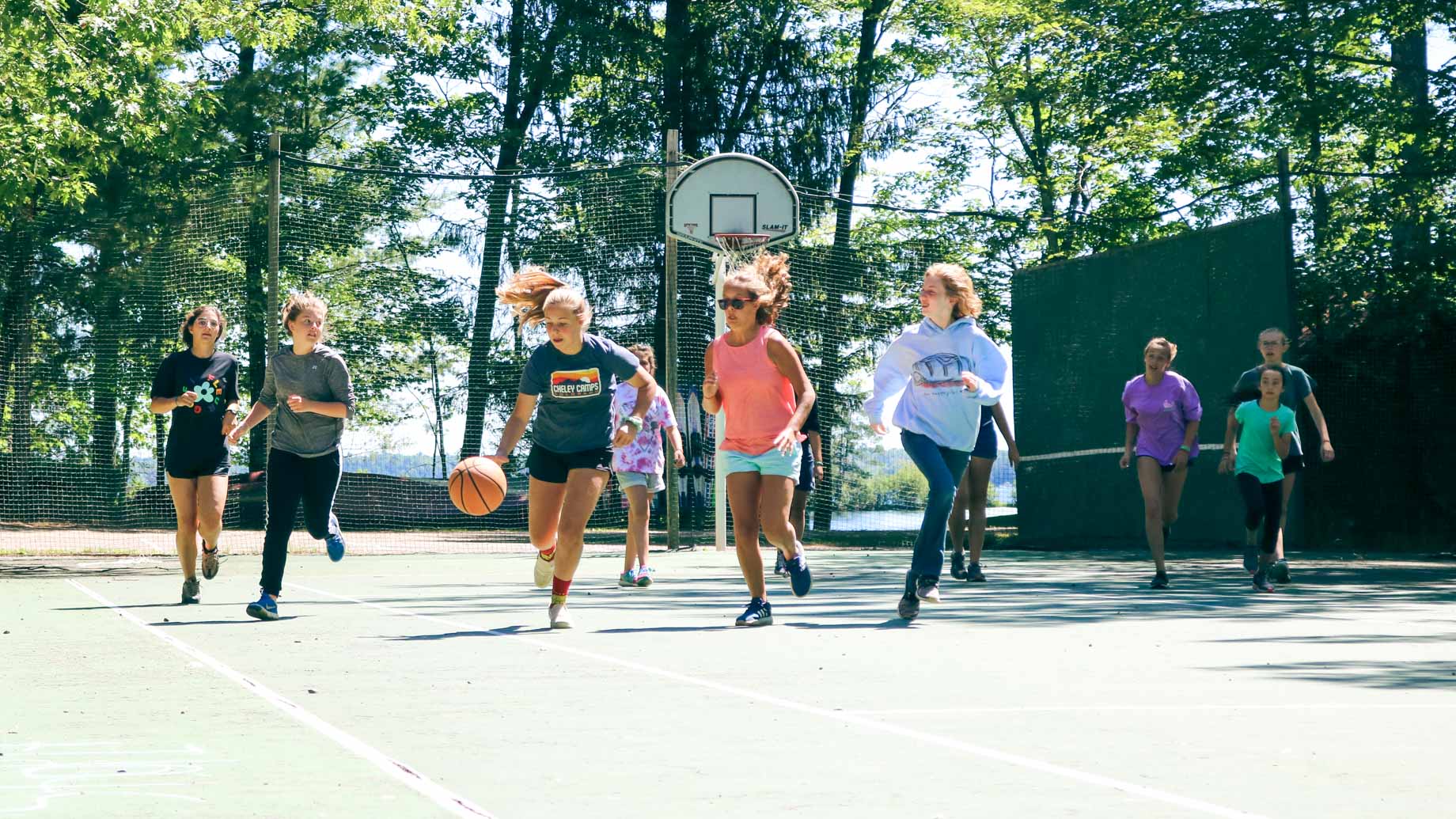 Girl dribbles basketball down court during camp game