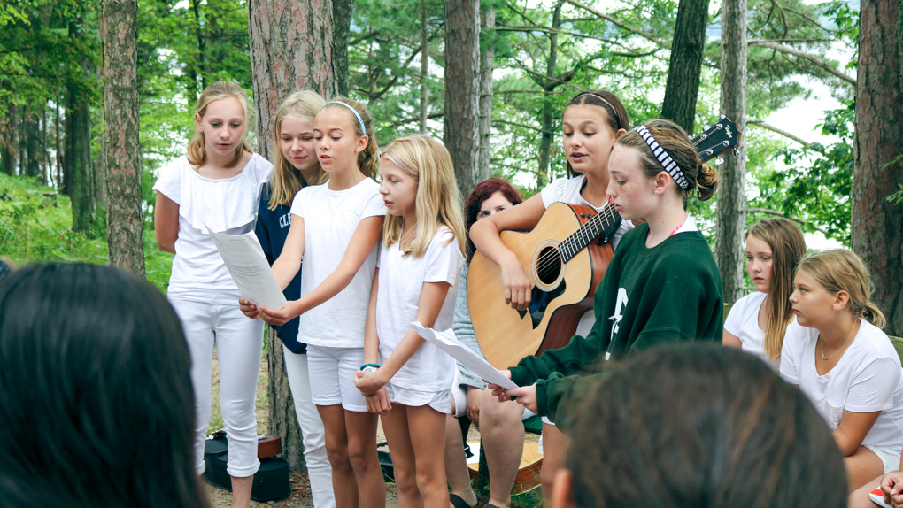 Campers perform song with guitar at Sunday Service