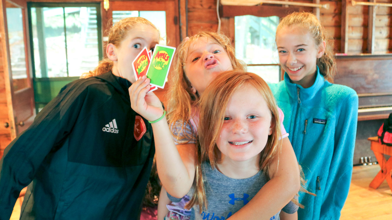 Group of campers makes silly faces with Apples to Apples cards