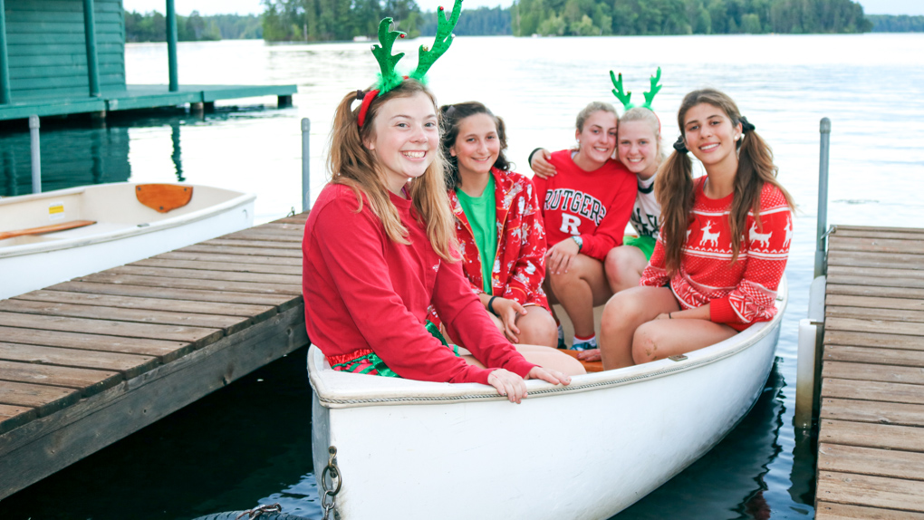 Campers in Christmas garb sit in docked canoe