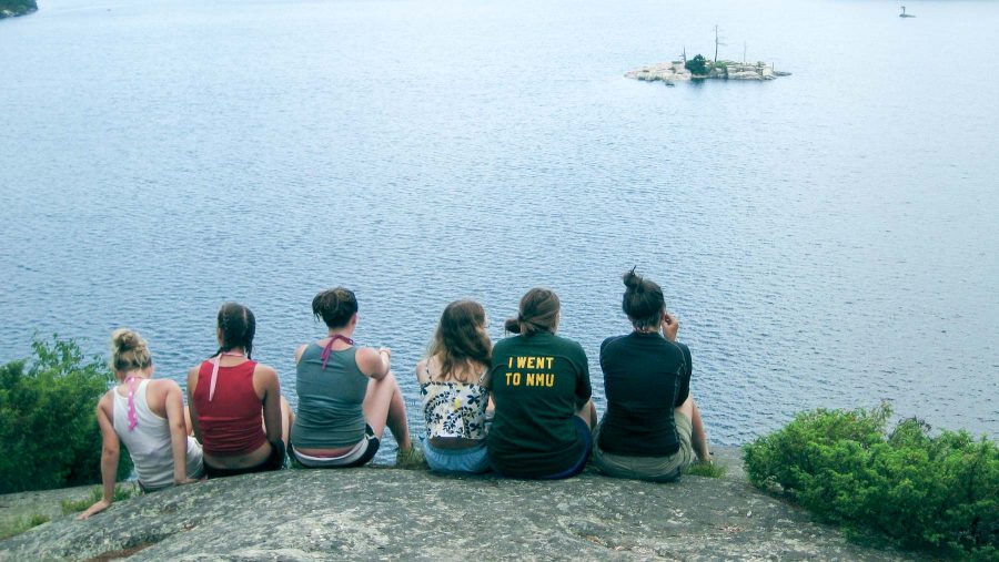 Campers sit on rock and overlook lake