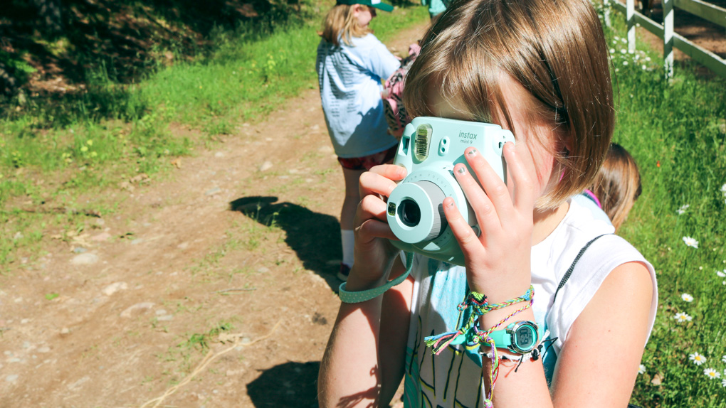 Young girl takes picture with turquoise camera