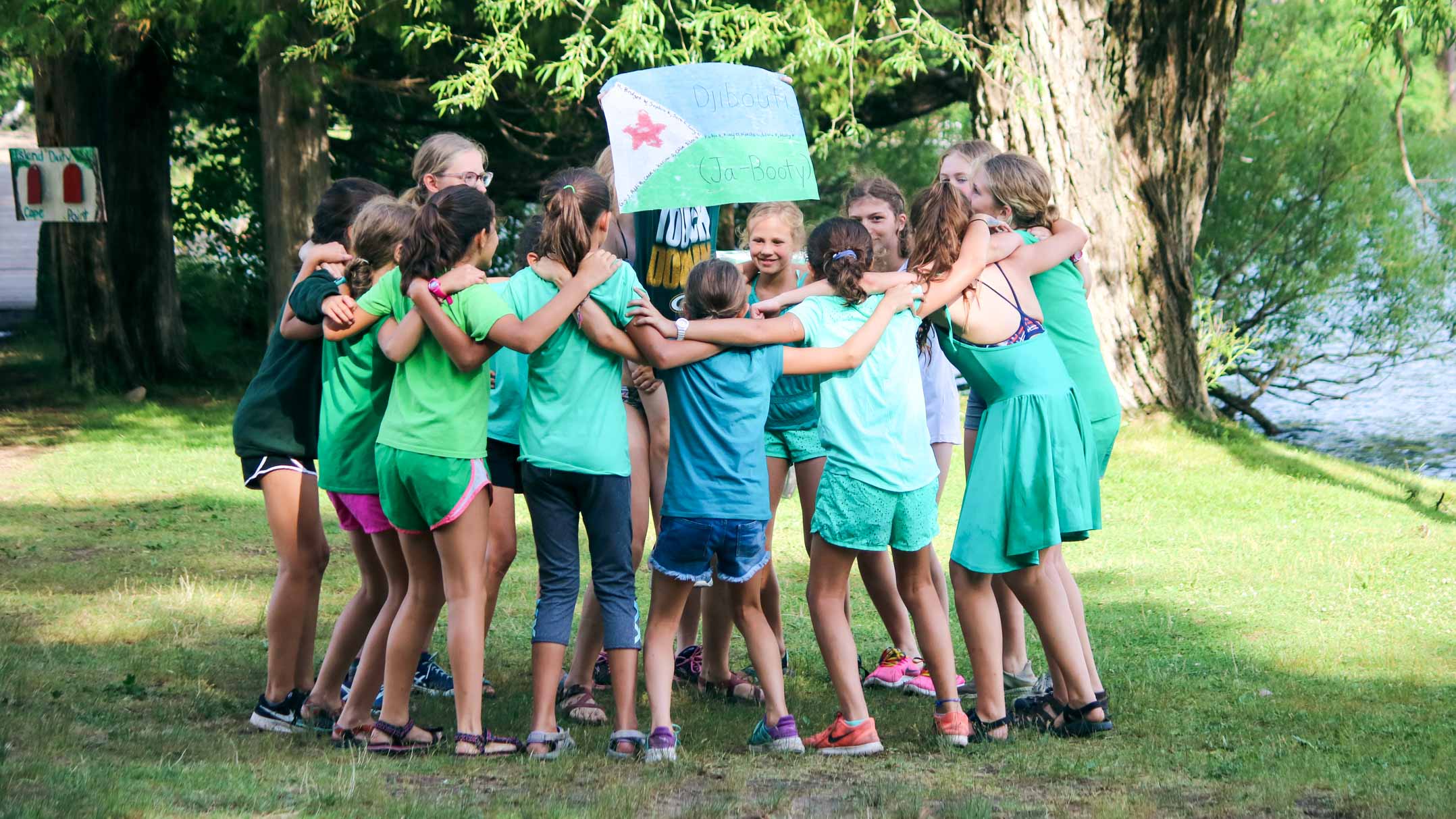 Group of campers circles up, holding camp Olympics Djibouti sign