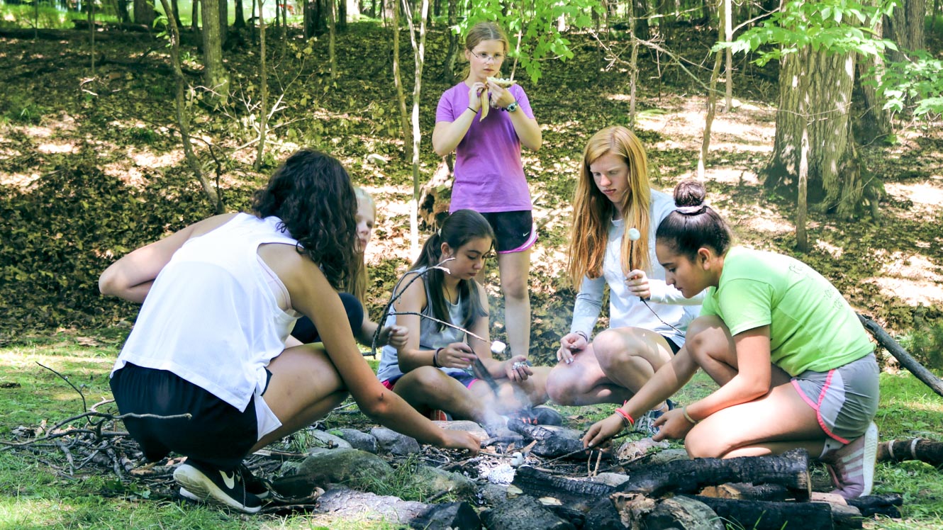 Group of campers cooks over outdoor fire