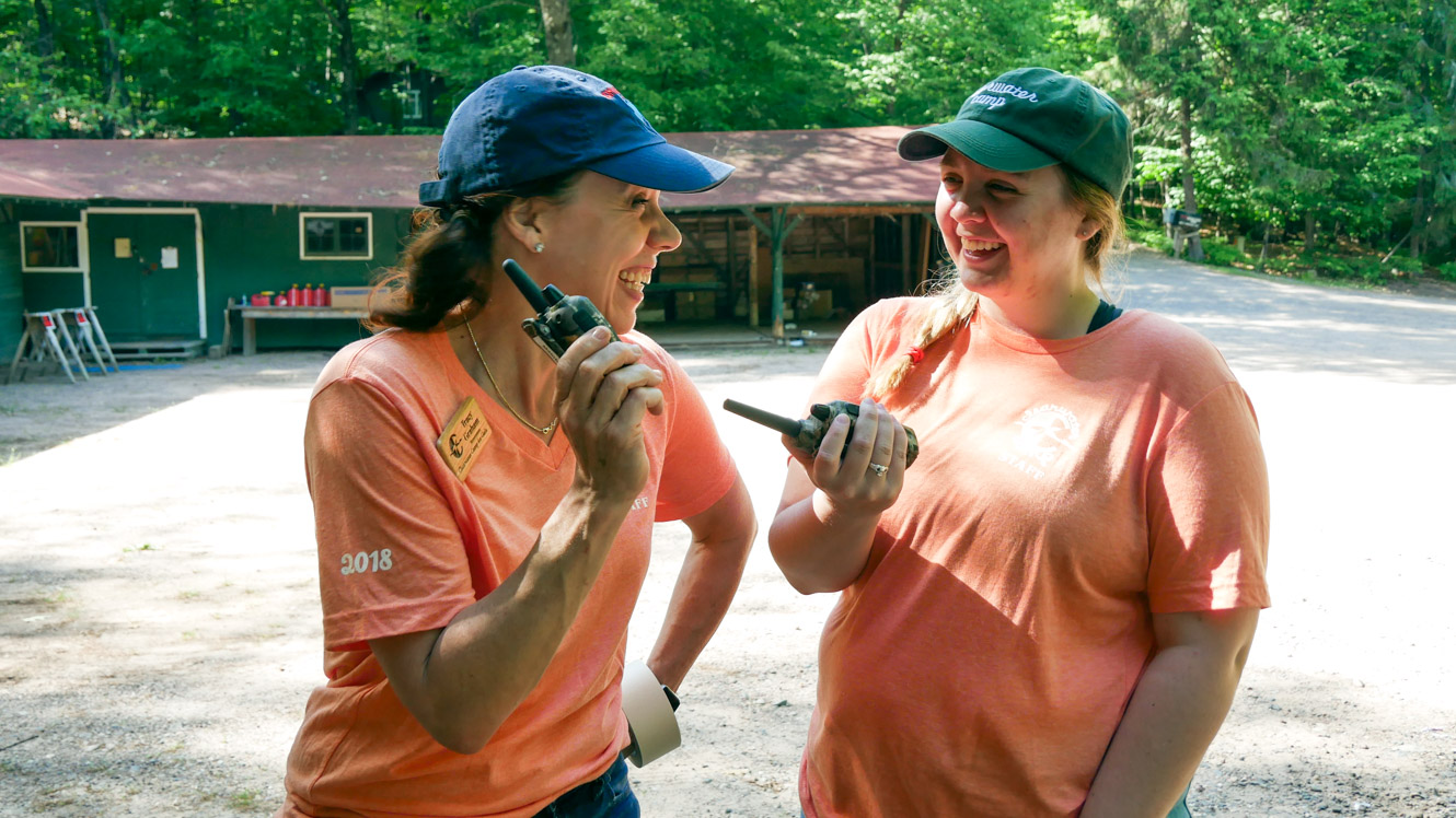 Camp staff laughing while holding walkie talkies