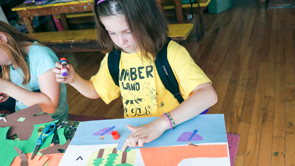 Young camper glues construction paper